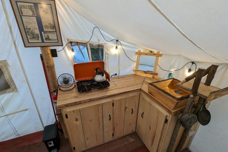 le coin cuisine de la tente prospecteur, avec son évier en bois, son poêle au propane et sa décoration d