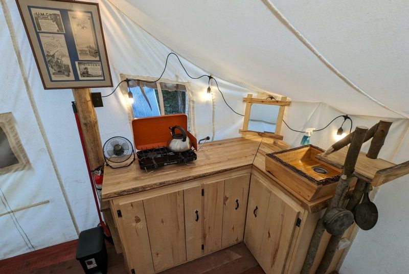 the kitchen area of the prospector tent, with its wooden sink, propane stove and period decoration