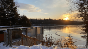 spa sur le bord d’un lac gelé au coucher du soleil, sous la neige qui reflète la lumière