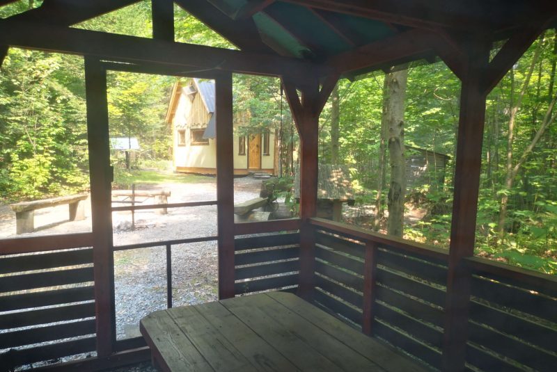 Outdoor dining shelters and fire pit in front of Eventyr, the Viking house available for rent in Quebec